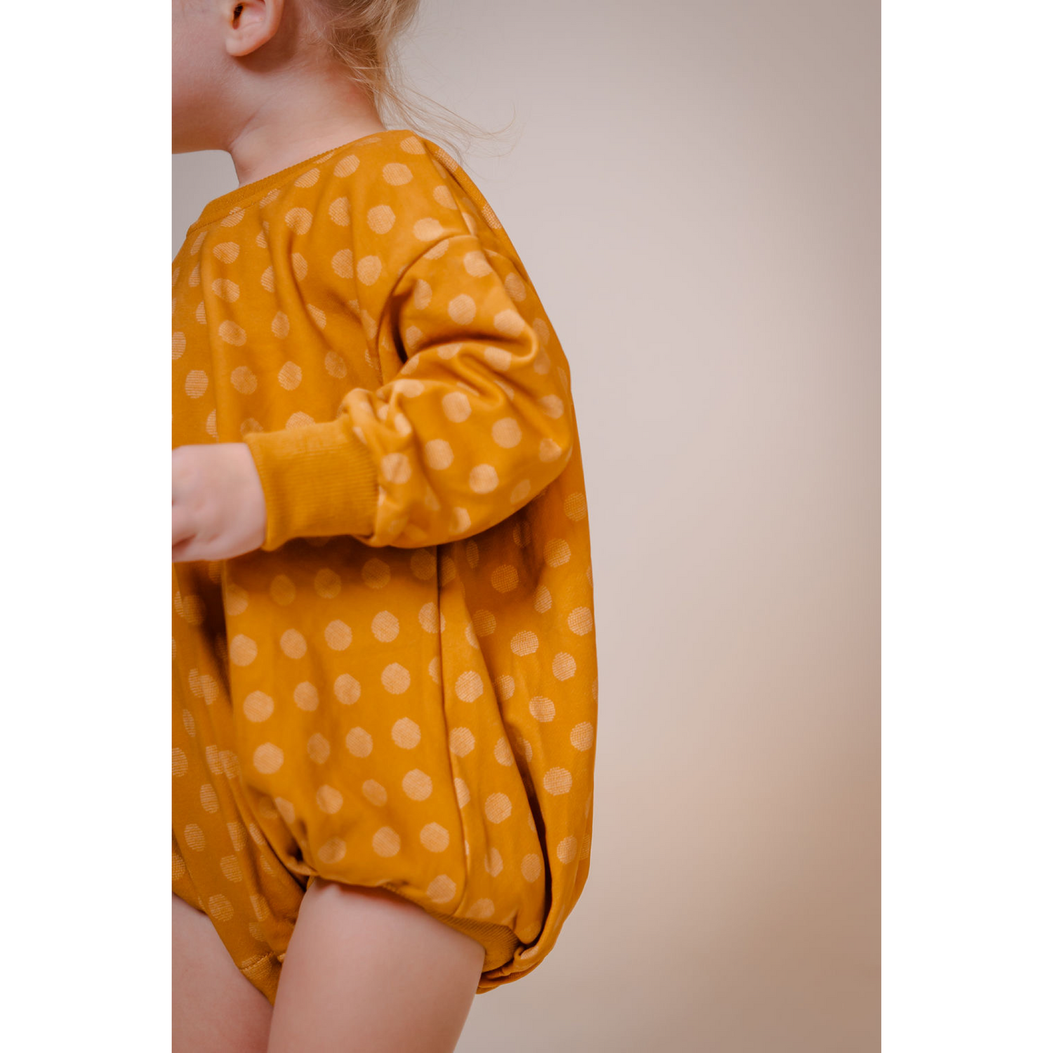 Toddler boy wearing a Soft, cotton sweater bubble in vibrant Mustard yellow abstract polka dot print