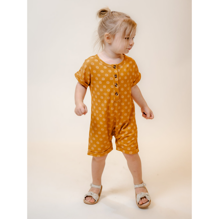 Toddler wearing our Soft, Bamboo Shortie Jumpsuit Romper in vibrant Mustard yellow abstract polka dot print
