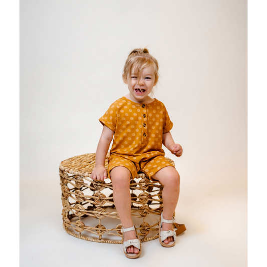 Toddler wearing our Soft, Bamboo Shortie Jumpsuit Romper in vibrant Mustard yellow abstract polka dot print
